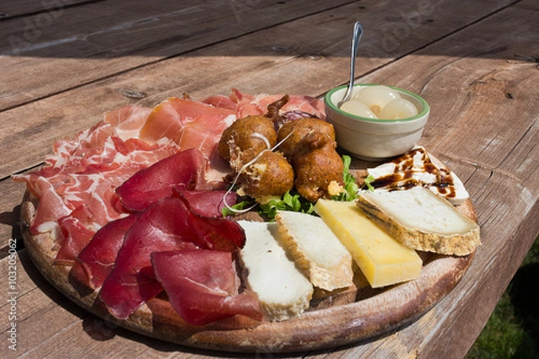 Obraz Valtellina - Typical culinary delights served at the alpine huts. The platter after trekking: speck,cheese,sciatt (buckwheat cheese fritters),ham, onion. Italy

