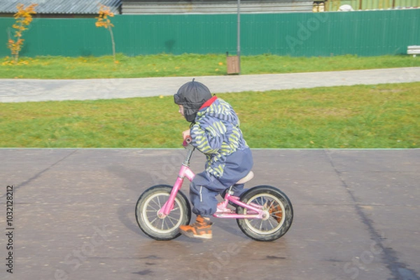 Fototapeta a child, a boy riding a running bike, a bicycle on a sports field, a photo without filters