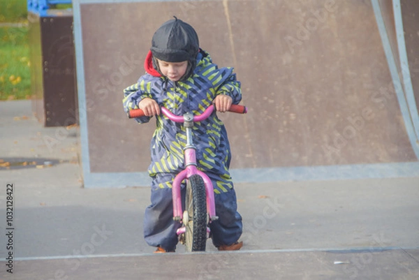 Fototapeta a child, a boy riding a running bike, a bicycle on a sports field, a photo without filters