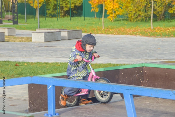Fototapeta a child, a boy riding a running bike, a bicycle on a sports field, a photo without filters