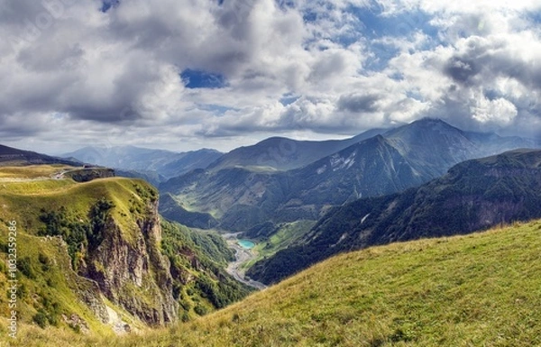 Fototapeta Scenic view of the Cross Pass in Georgia, showcasing lush green mountains and a winding valley