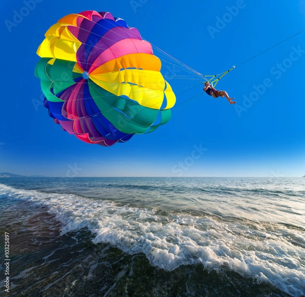 Fototapeta Man is parasailing in the blue sky