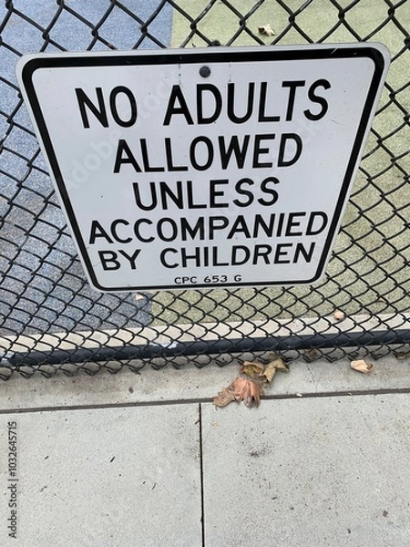 Obraz This photo captures a sign posted at a children's playground that reads, "No Adults Allowed Unless Accompanied by Children." The sign is mounted on a chain-link fence.