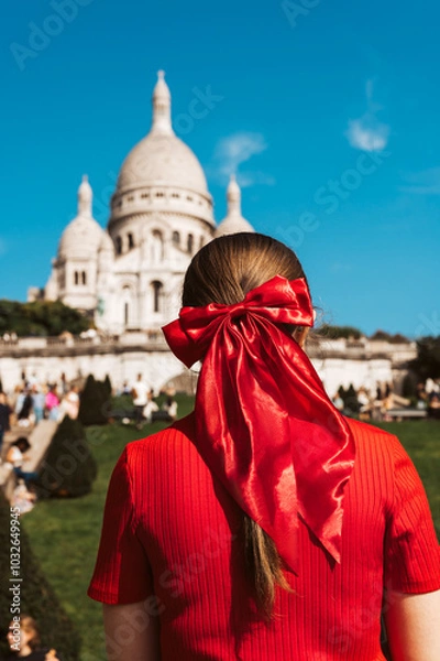 Fototapeta Tourist Girl with red bow in her hair is watching Basilica of Sacre Coeur de Montmartre, commonly known as Sacre-Coeur Basilica, in Paris