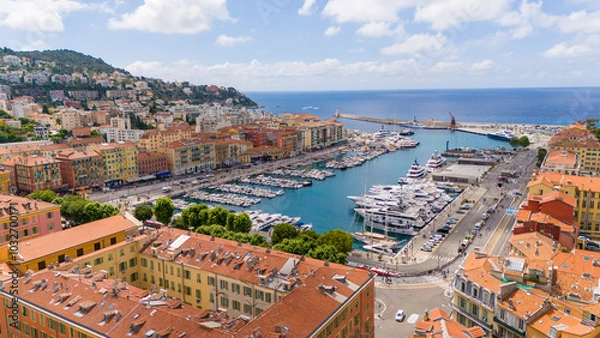 Fototapeta Aerial view of Nice, France, showcasing the vibrant Port of Nice, with colorful buildings, yachts, and a scenic Mediterranean backdrop. The city blends historic charm with coastal beauty