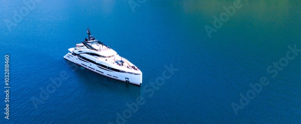 Fototapeta A snow-white modern yacht stands at anchor in an azure bay