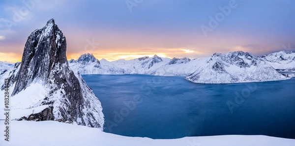Fototapeta Panorama of Segla mountain peak and Fjord seen from Hesten trail near Fjordgard on Senja island, Norway in winter. Scenic winter landscape with snowy mountains range and cold fjord water at sunset