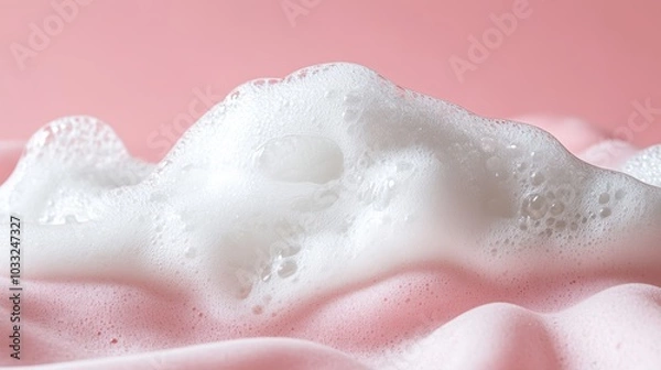 Fototapeta Fluffy white shampoo bubbles against a soft pink background, emphasizing cleanliness and softness.