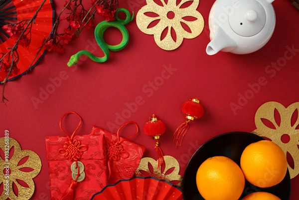 Fototapeta Chinese New Year concept with teapot, oranges, red envelopes, and lanterns on a red background