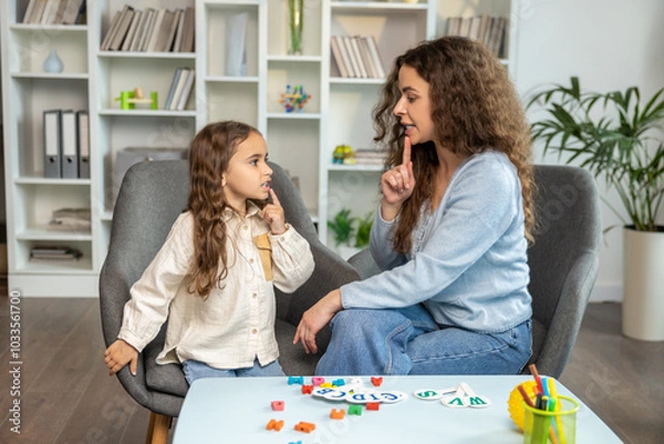 Fototapeta Speech therapist working with a girl and both looking involved