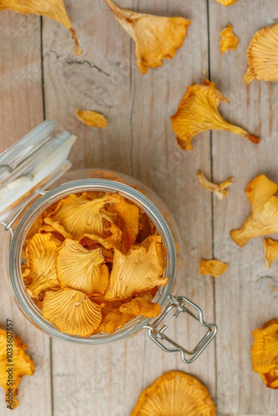 Fototapeta Dried chanterelles in a glass jar on a wooden table. Useful forest mushrooms. Cantharēllus cibārius. Selective focus
