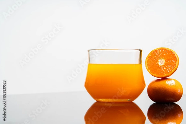 Fototapeta Vertical image of delicious freshly squeezed orange juice in the glass from organic oranges isolated on white background with copy space