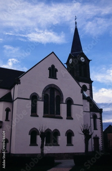 Obraz View of Protestant Parish of Plobsheim with clock tower  in Plobsheim north-eastern France during 2000s