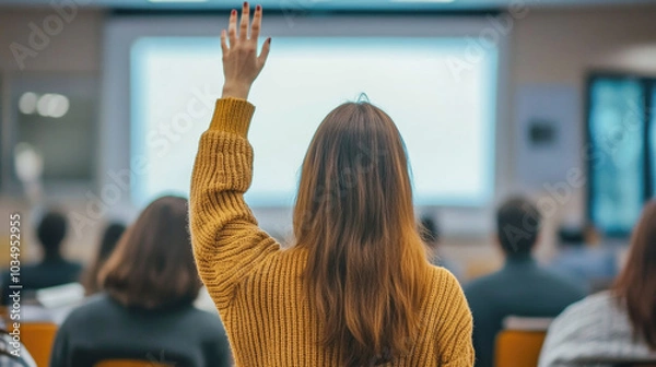 Fototapeta Student raising hand in classroom to ask question during lecture or presentation