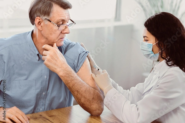 Obraz Seasonal Flu Shot. Brazilian nurse in medical mask injecting tetanus toxoid vaccine to senior retired man, copyspace