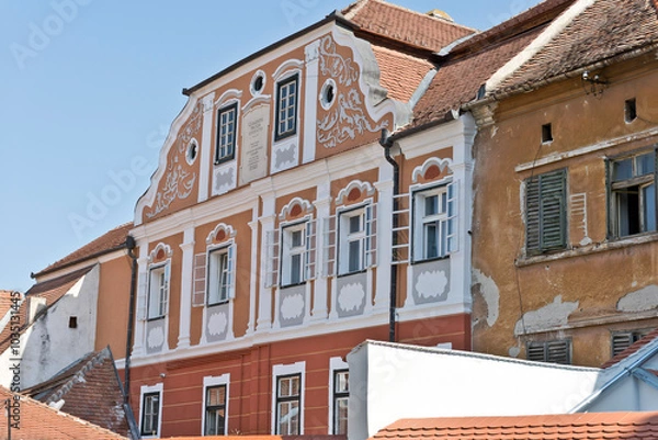 Fototapeta A colorful facade of a historic building in Sibiu, Romania. There is a plaque with Latin inscription and the name "JOHANNES GEORGA SOHAGER" above the windows.