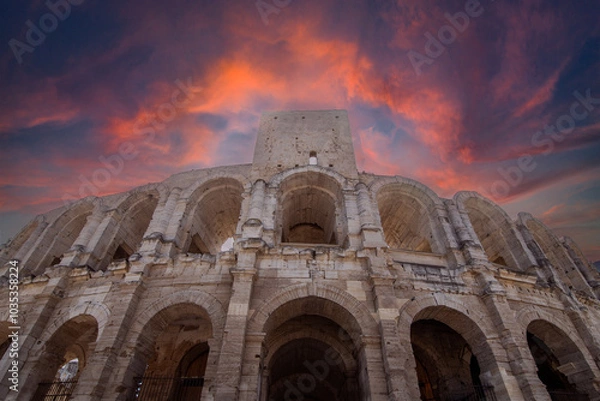 Fototapeta The Arles Roman Amphitheater stands against a fiery sky, reflecting the grandeur of its ancient past. This iconic structure symbolizes the timelessness of Roman engineering and history.