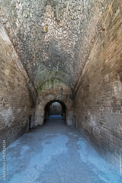Fototapeta Wander through the ancient stone pathways of the Arles Roman Era Amphitheater, where cave-like passages and carved steps create a mystical journey. Each step echoes with history, inviting exploration

