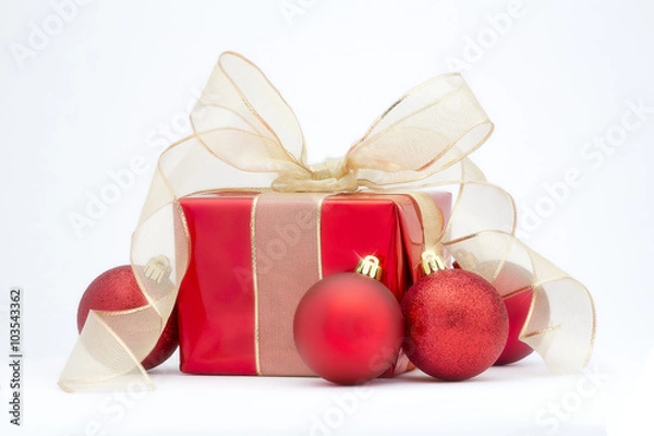 Fototapeta A red Christmas present with gold ribbon and red tree decoration