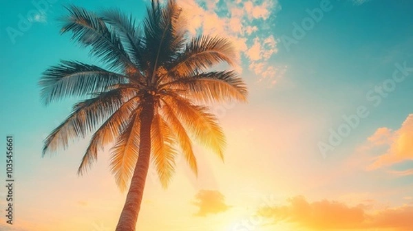 Fototapeta Majestic palm tree silhouette against a vibrant sunset sky, with golden sunlight filtering through fronds, creating a tropical paradise ambiance on a serene beach.