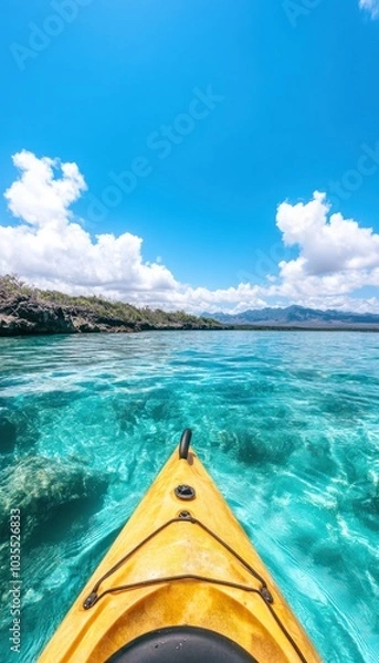 Fototapeta A kayak glides over crystal-clear turquoise water under a bright blue sky with fluffy white clouds.