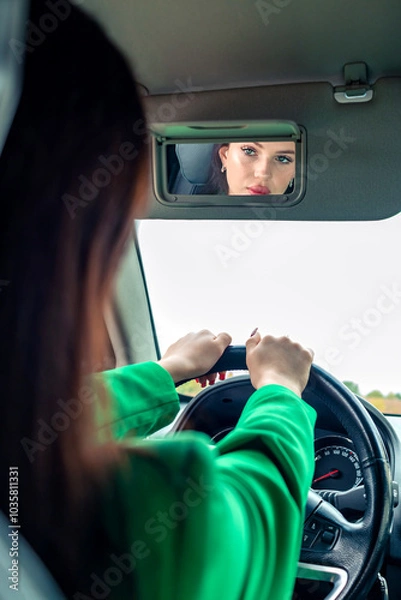 Obraz A girl in a green jacket driving a car.