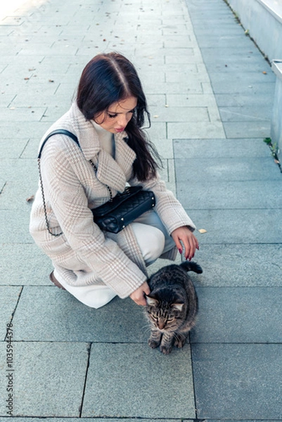 Obraz A girl pets a street cat.