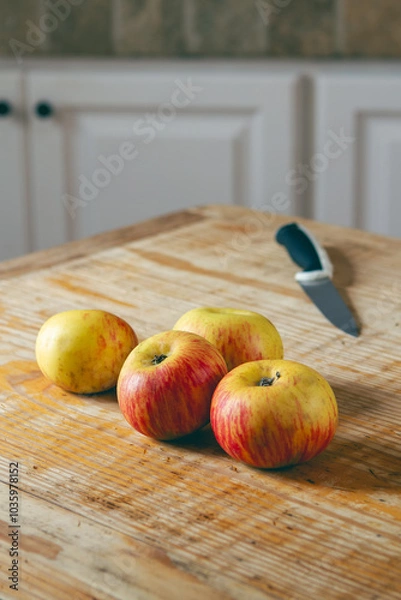 Fototapeta apples on a rustic wooden table with kitchen knife