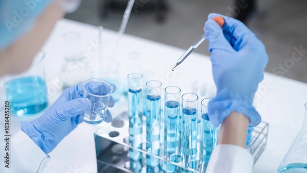 Fototapeta Close-up hands dropping fluid from dropper flask beaker into blue test tube sample laboratory for compare in medicine chemical biology medical science experiment technology biotechnology analysis