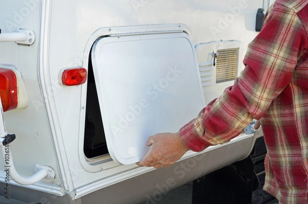 Obraz Man opening the storage bin of a camper.