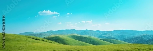 Fototapeta Serene mountain landscape under clear blue sky with rolling green hills.