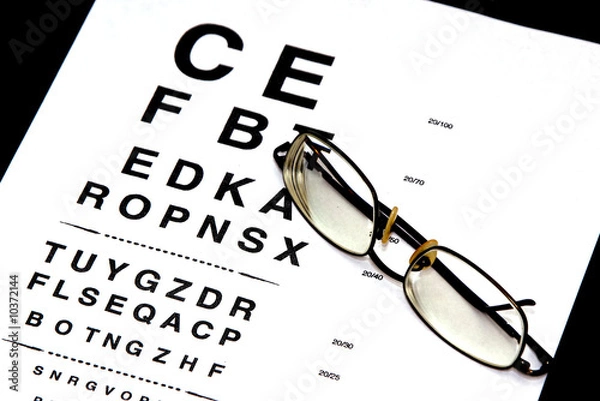 Obraz modern eyeglasses resting on eyechart with frame closed