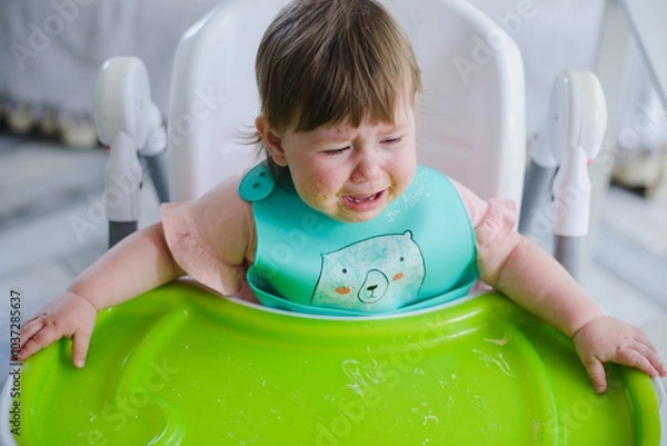 Fototapeta A small child is crying at the table. He doesn't want to eat