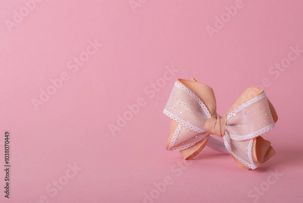 Fototapeta A beautiful bow made of turnip ribbon on a light pink background. copy space.