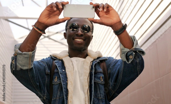 Obraz Stylish happy African young man taking selfie with phone, black american guy smile using smartphone