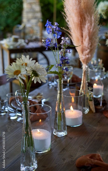 Fototapeta Wedding decoration. Floristics. Vessels with candles and bulk wax. Transparency and ease of design. Blue flowers and pampas.
