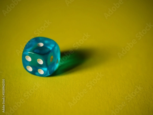 Fototapeta Blue dice on yellow paper background. Cardboard bright background with texture. Concept of luck, testing fate, lottery, decision making. Place for text. Copy space. Rovinj, Croatia - October 4, 2024