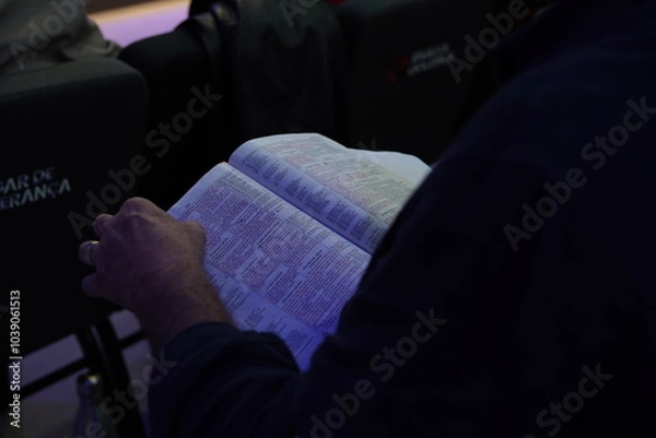 Fototapeta Close-up of a man's hands holding a Holy Bible, symbolizing faith and devotion. The image captures the essence of spirituality and reflection, inviting a deeper connection to religious traditions.