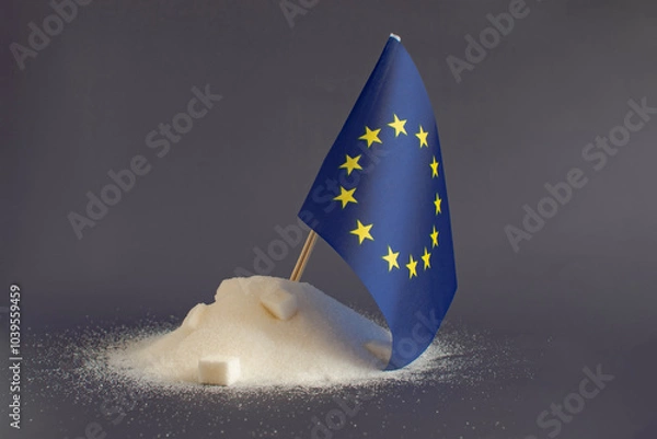 Fototapeta A mountain of granulated sugar and the flag of the European Union in close-up on a light background. Europe is one of the main sugar producers in the world.