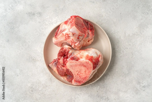 Obraz Raw beef bones for making broth in a white plate on a culinary kitchen table top view with a copyspace