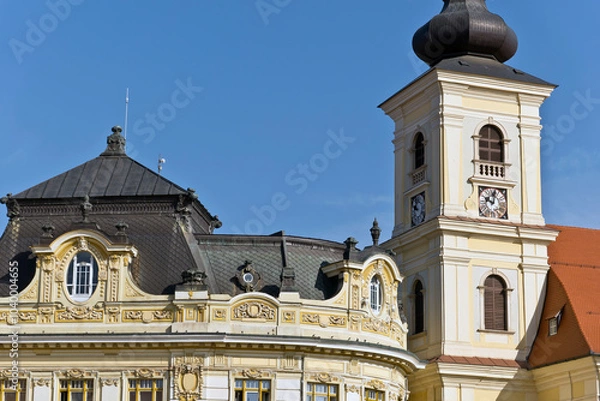 Fototapeta A baroque-style church tower in Sibiu, Romania, featuring an onion-shaped dome, a clock face, and arched windows.