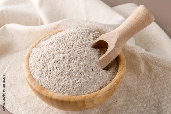Obraz Buckwheat flour in a wooden bowl and raw buckwheat grain on cotton napkin on beige monochrome background. Alternative flour, gluten free flour, healthy nutrition