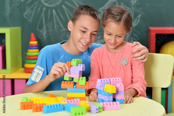 Fototapeta Little brother and sister assemble a construction set at home
