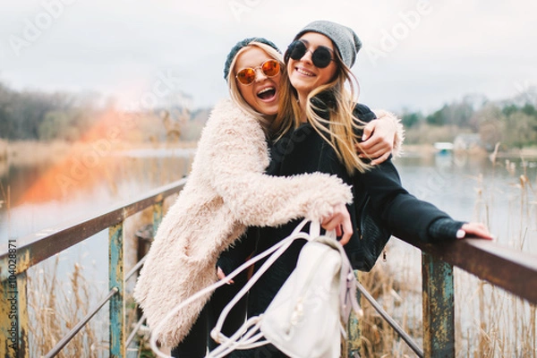 Obraz Outdoor lifestyle portrait of two best friends, smiling and having fun together, enjoy each other company posing and making selfie pictures to each other and share happiness
