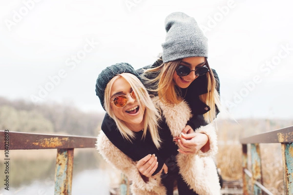 Obraz Outdoor lifestyle portrait of two best friends, smiling and having fun together, enjoy each other company posing and making selfie pictures to each other and share happiness
