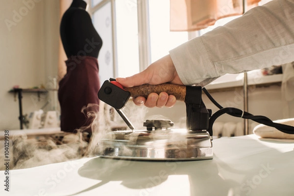 Obraz dressmaker stroked the fabric with steam iron