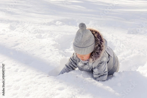 Fototapeta Little girl playing with snow in the winter park. Winter activities for children. Cute kid has fun ourdoor in winter park