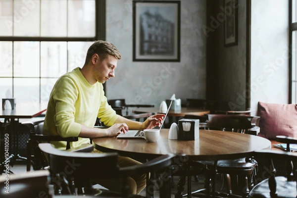 Obraz Young man performs work on a laptop