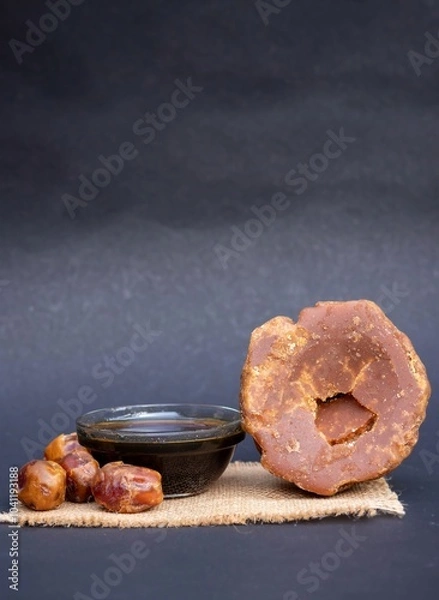 Obraz Date Palm Jaggery and Khejur Gur in a Glass Bowl and Date Palm Fruit Isolated on Black Background with Copy Space