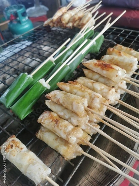 Fototapeta Grilled Squid Eggs, a Thai street food is usually eaten with seafood sauce. Mix squid eggs with seasoning sauce wrapping them in banana leaves and skewering them to grill.